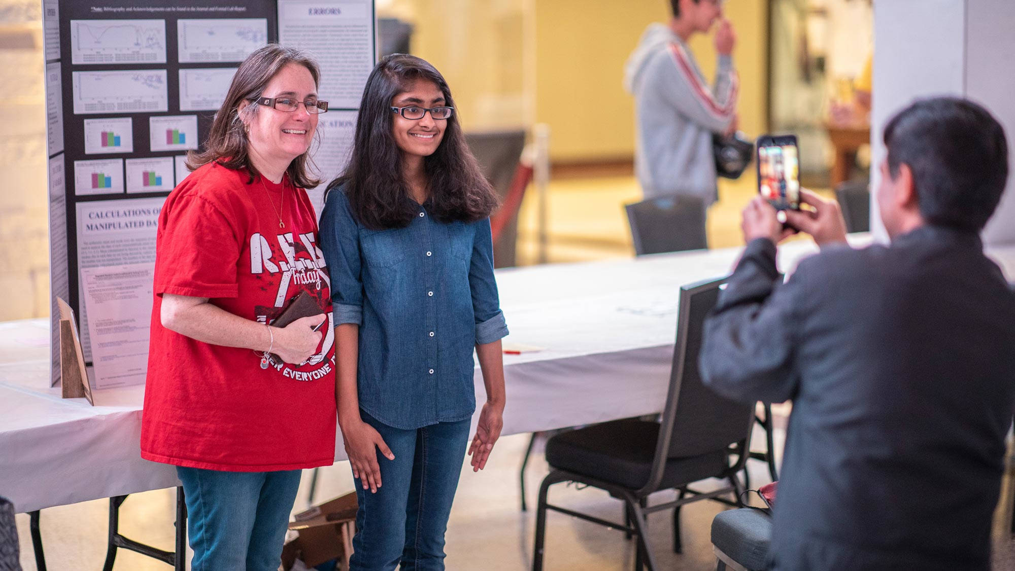 A young girl and boy, both with brown hair, kneel on the ground as they work on a poster as the 2019 Texas Science and Engineering Fair.